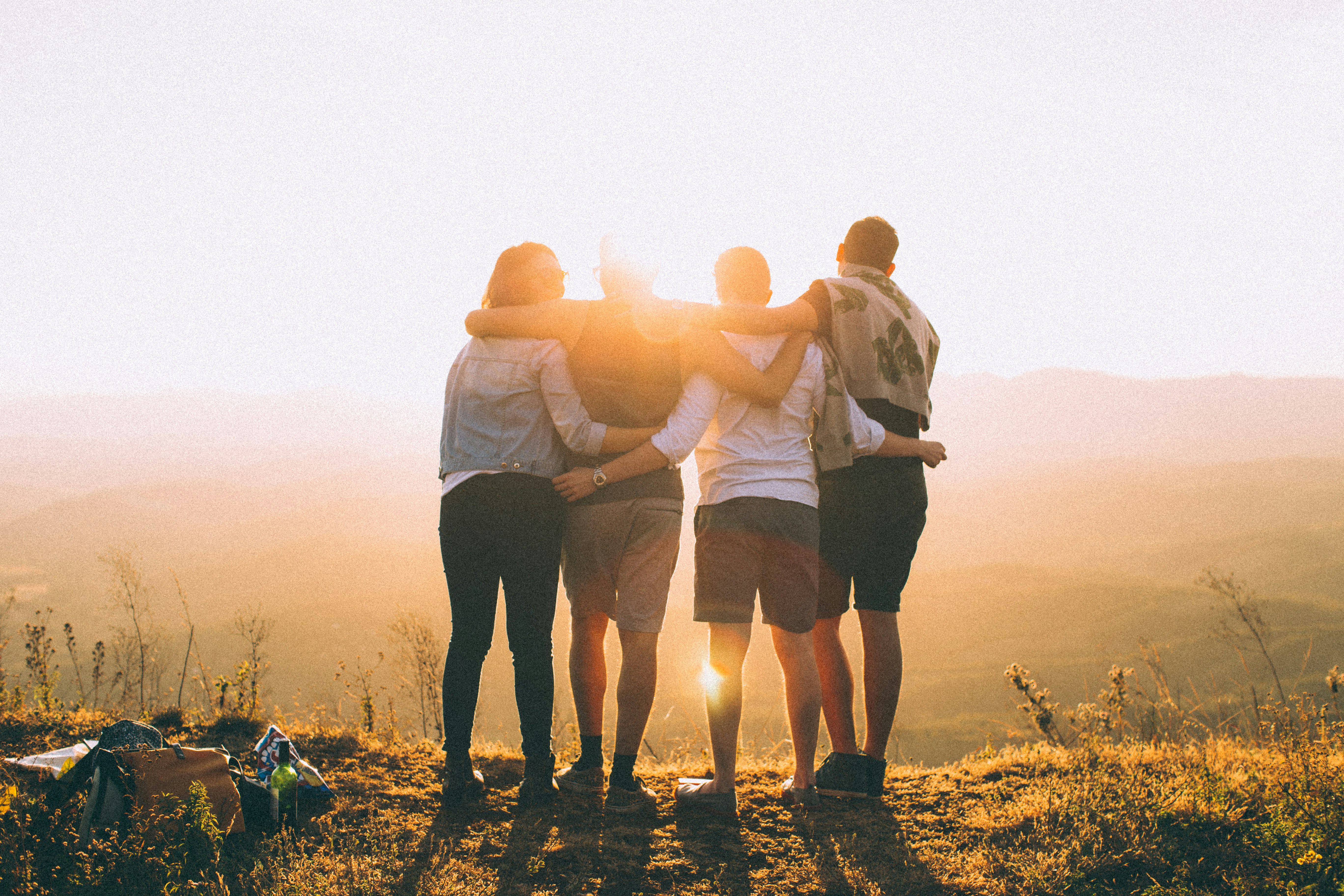 Group of four people embracing at sunset