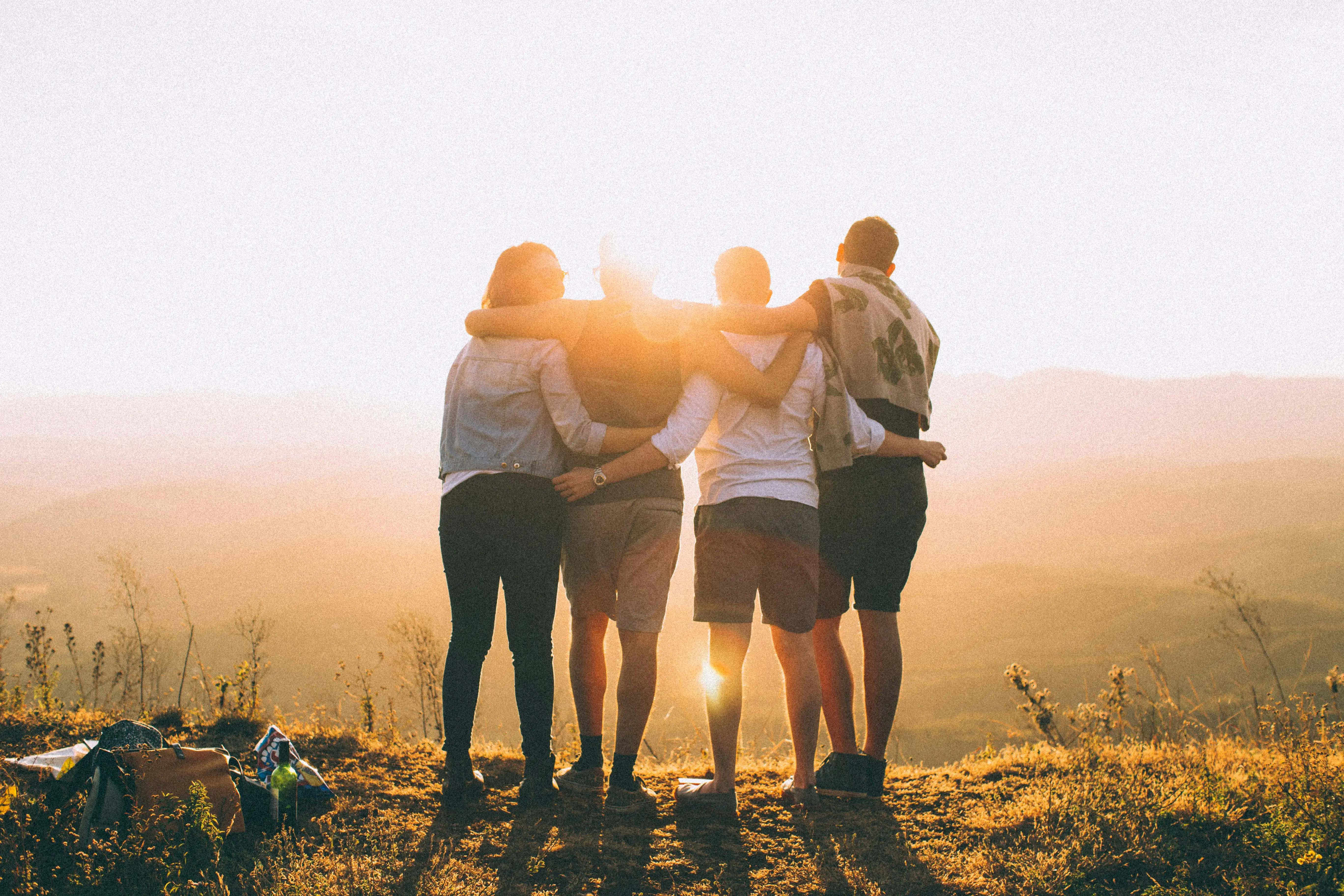 Group of four people embracing at sunset